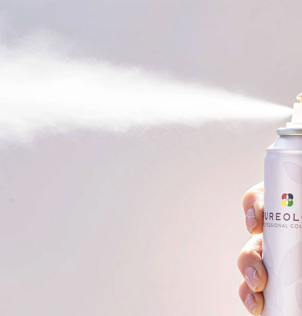 Model's hand dispenses Pureology Style + Protect Texture Finishing Spray