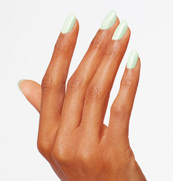Model's hand wears a light shade of green nail polish