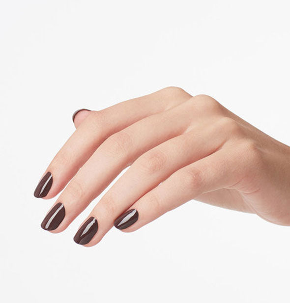 Model's hand wears a dark shade of earthy brown nail polish