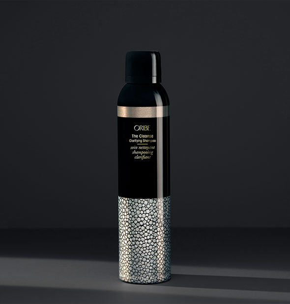  Black, gold, and silver bottle of Oribe The Cleanse Clarifying Shampoo on dark gray background