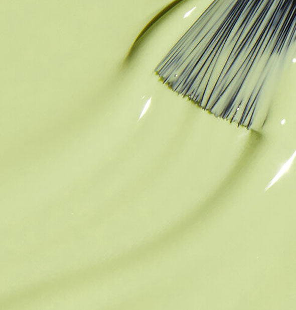 Light green nail polish with a brush tip dipped in it