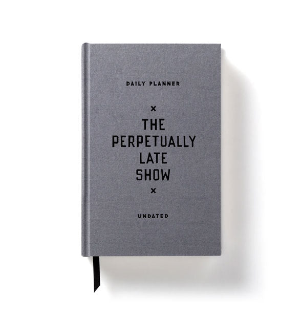Gray cloth-bound undated  Daily Planner: The Perpetually Late Show with ribbon place marker sticking out from the bottom