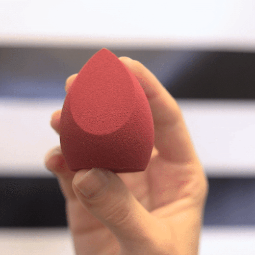 Model's hand squeezes The Sponge by Makeup Eraser to show its texture and density