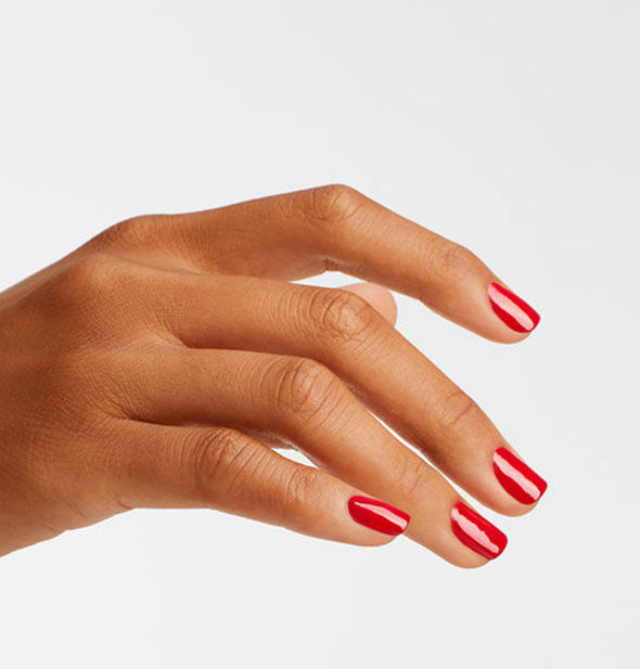 Model's hand wears a brilliant red shade of nail polish