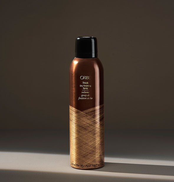 Brown and gold can of Oribe Thick Dry Finishing Spray on dark background