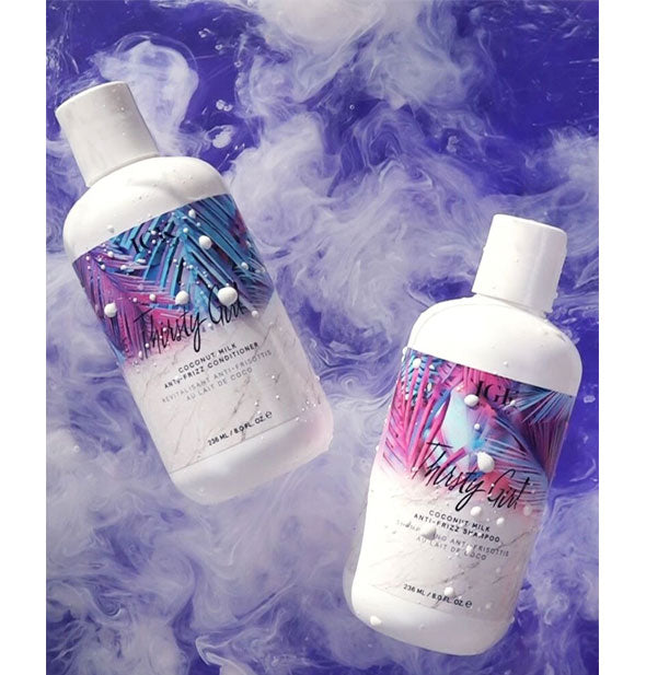 Bottles of IGK Thirsty Girl Coconut Milk Anti-Frizz Shampoo and Conditioner staged amid milky swirls of product on a purple background