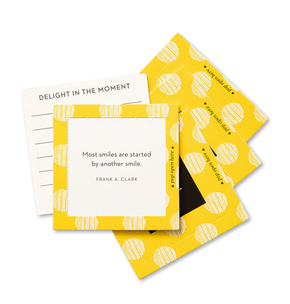 Stack of square yellow cards with topmost one featuring a quote by Frank A. Clark: "Most smiles are started by another smile." Another card says, "Delight in the moment"