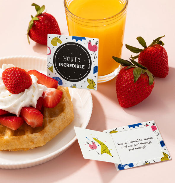 You're Incredible cards are staged with a glass of orange juice, strawberries, and plate with waffle topped with whipped cream and strawberries