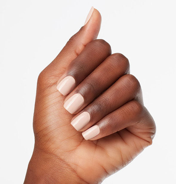 Model's hand wears a creamy shade of off-white nail polish