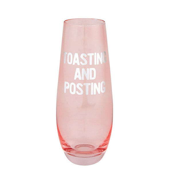 Stemless pink glass champagne flute printed with "Toasting and Posting" in metallic silver lettering