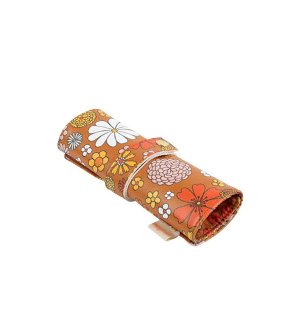 Brown brush roll with floral print is secured with a strap with gold snap