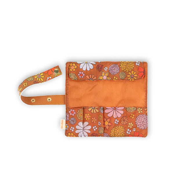 Brown floral brush roll unfolded to reveal interior with pockets and a side strap