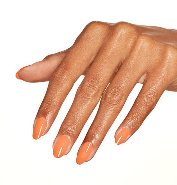 Model's hand wearing muted orange nail polish