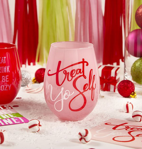 Treat Yo Self pink stemless wine glass staged with peppermint candy and other colorful party accoutrements