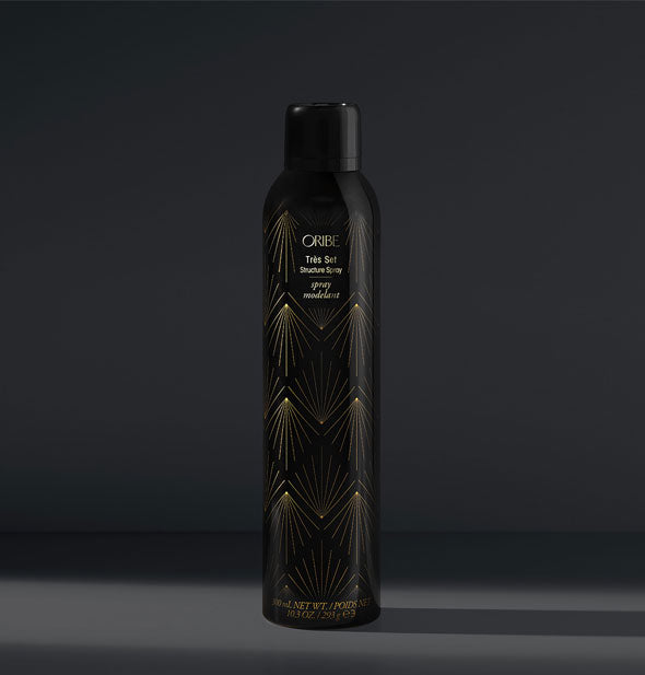 Black can of Oribe Très Set Structure Spray with gold accents on a dark gray background