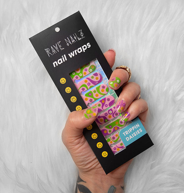 Model's hand holds a pack of Rave Nailz Trippin Daisies Nail Wraps