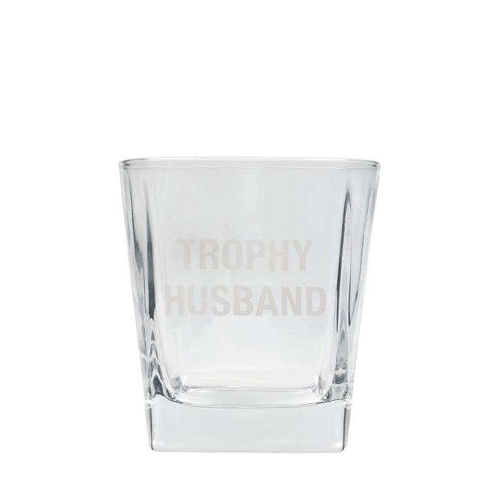 Rocks glass printed with "Trophy Husband" in very light all-caps lettering
