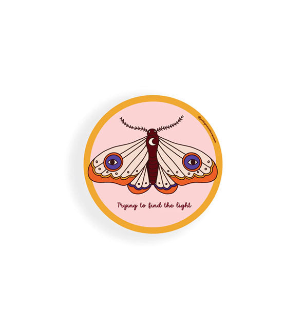 Round pink sticker with orange border features illustration of a moth above the words, "Trying to find the light" in small script