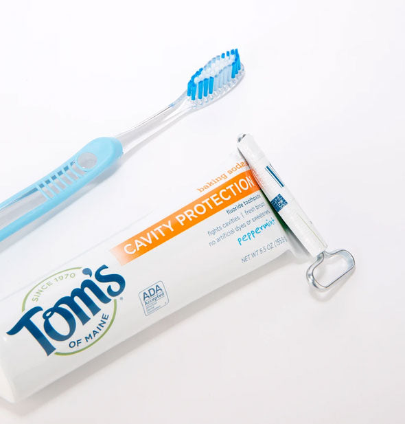 A tube key is shown wrapped up in the bottom of a toothpaste bottle to condense product inside
