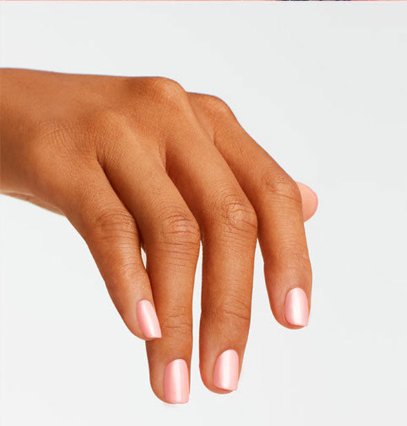 Model's hand wears a pearly shade of pink nail polish