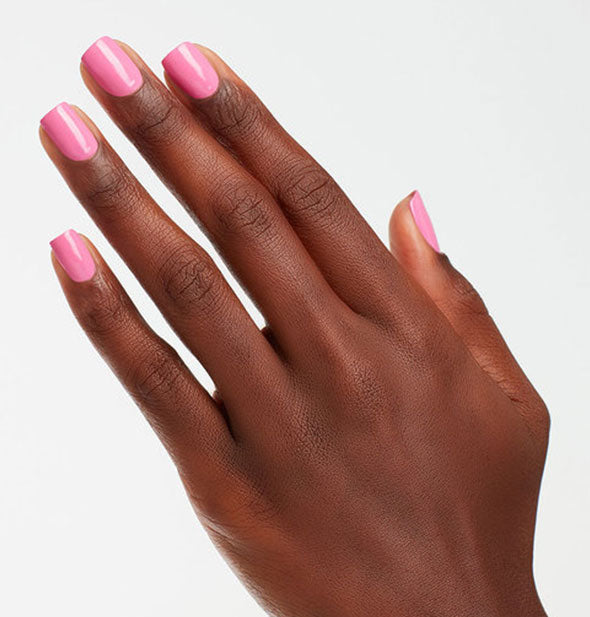 Model's hand wears a classic shade of pink nail polish