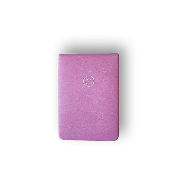 Pink notepad cover with white stamped smiley face near top center