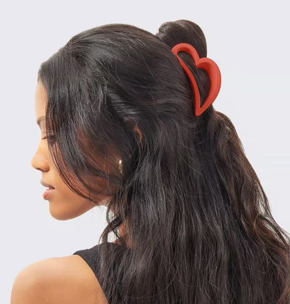 Model wears a red heart-shaped hair clip in a half-up style