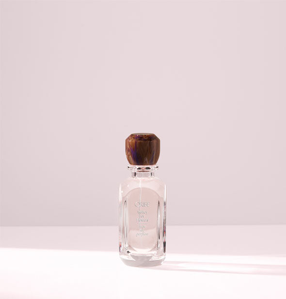 Clear glass bottle of Oribe Valley of Flowers Eau de Parfum with brown marble-effect beveled cap