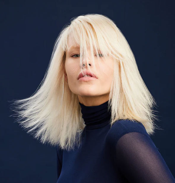 Model with platinum blonde shoulder-length hair flaring out mid-motion