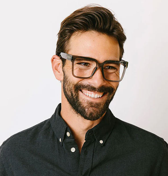 Smiling model wears a pair of dark gray square glasses