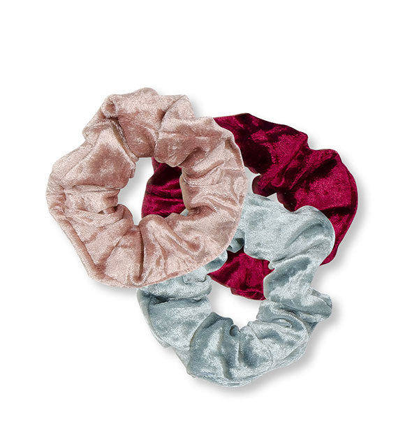 Three velvet hair scrunchies in gray, pink, and red