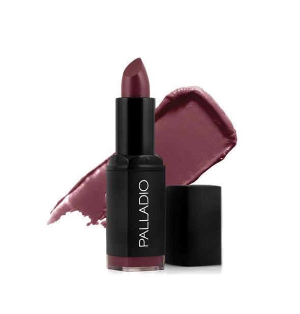 Black tube of Palladio lipstick with cap removed and color swatch behind in a dark brownish-purple shade called Velvet Wine