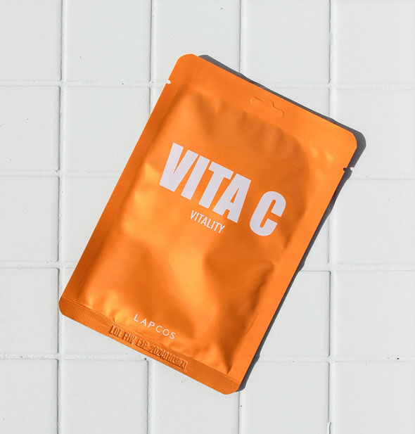 Orange Vita C Vitality sheet mask pack rests on a white tiled surface