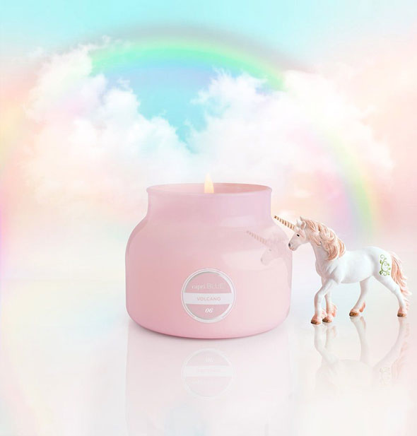 Lit pink jar candle on a puffy white cloud and blue sky background with rainbow and unicorn