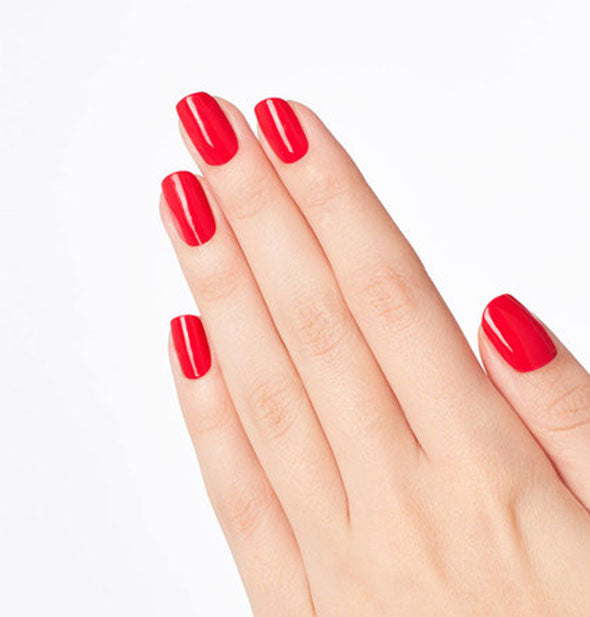 Model's hand wears a vibrant red shade of nail polish