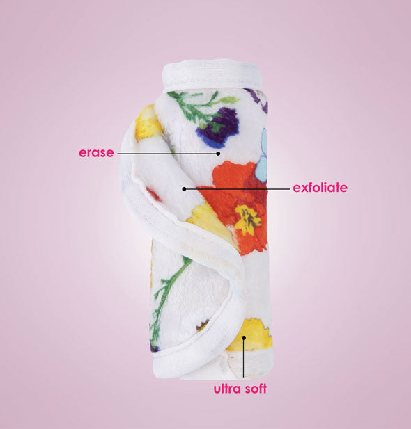 Rolled up floral print white MakeUp Eraser cloth is labeled, Erase, Exfoliate, Ultra Soft