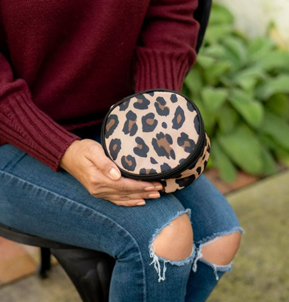 Model holds a round leopard print jewelry case in hands