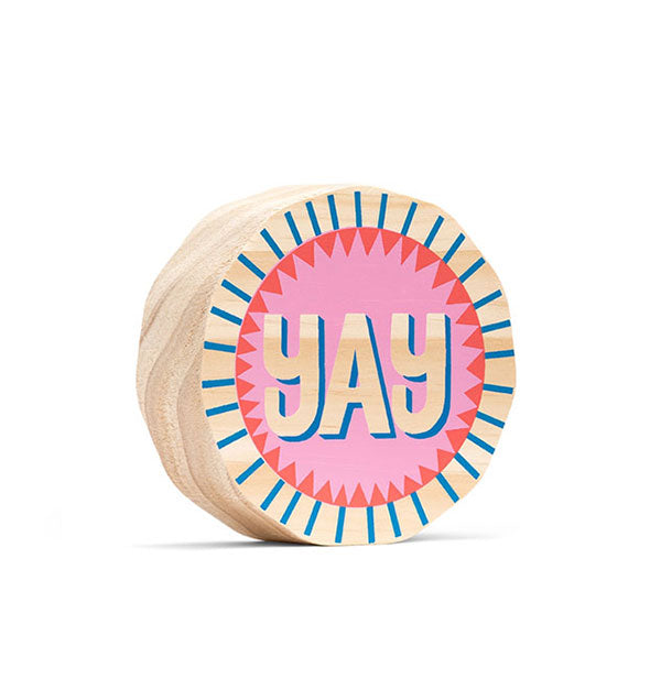 Round free-standing wooden sign painted blue, pink and red says "Yay" in the middle