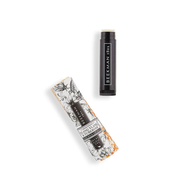 Black tube of Beekman 1802 lip balm next to its decorative packaging