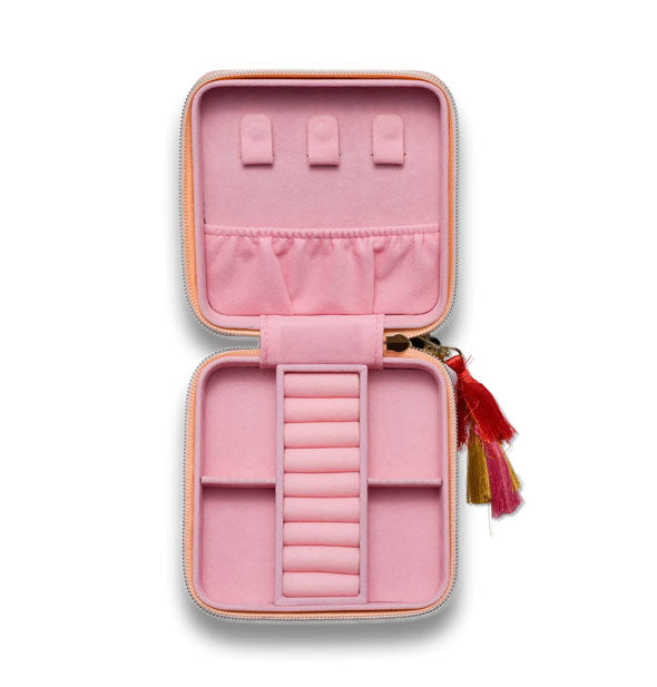Open square case with pink interior has various slots and sections for jewelry storage; a colorful tassel zipper pull extends to the side