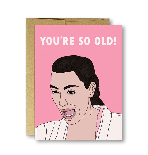 Pink greeting card on top of kraft envelope features an illustration of Kim Kardashian crying under the words, "You're so old!" in white lettering