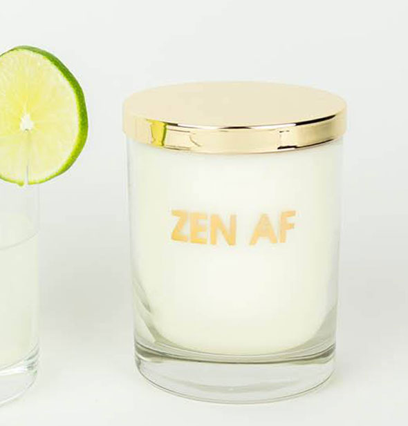 Glass candle jar with shiny gold lid says, "Zen AF" on the side in metallic gold lettering