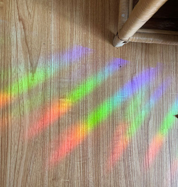 Rainbows cast across a laminate floor from a prismatic window decal